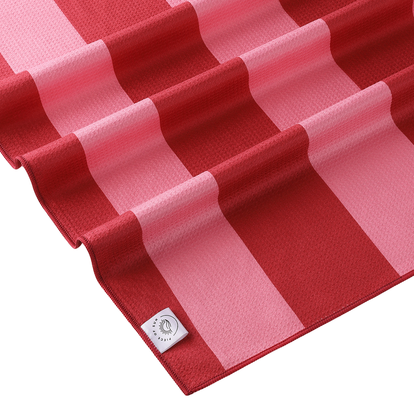 Detail van het microvezel strandlaken van Piece of Sun met roze en donkerroze strepen. Luxe wafelstructuur, ultrazacht en sneldrogend materiaal van 85% gerecycled textiel – duurzaam en comfortabel.