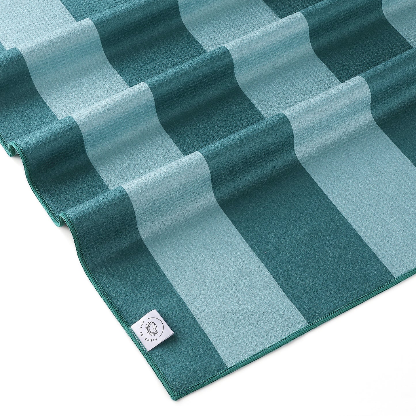 Detail van het turquoise-petrol gestreepte strandlaken van Piece of Sun. Luxe microvezel met wafelstructuur, gemaakt van 85% gerecycled materiaal – ultrazacht, lichtgewicht en sneldrogend.