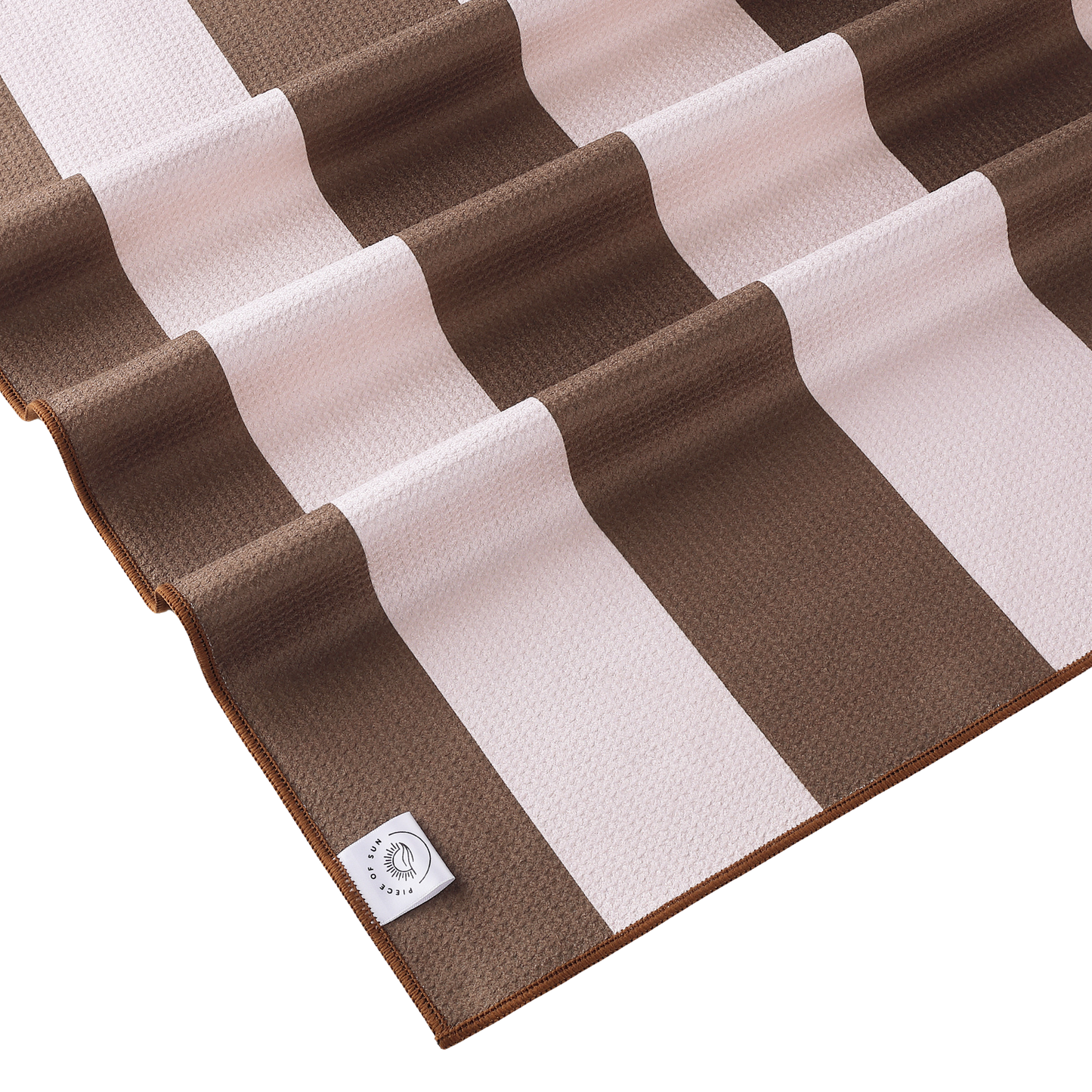 Close-up van het beige-witte gestreepte strandlaken van Piece of Sun. Gemaakt van luxe microvezel met wafelstructuur, ultrazacht, sneldrogend en duurzaam door 85% gerecycled materiaal.