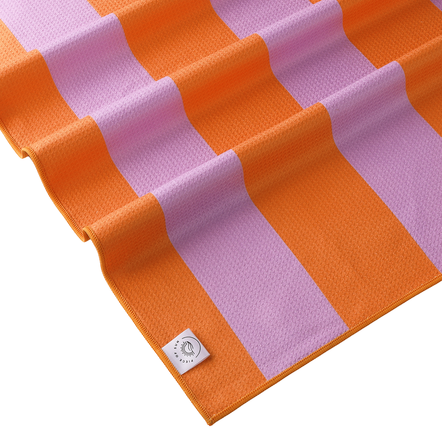 Close-up van het lila-oranje gestreepte strandlaken van Piece of Sun. Luxe microvezel met wafelstructuur, extra zacht, sneldrogend en duurzaam dankzij 85% gerecycled materiaal.