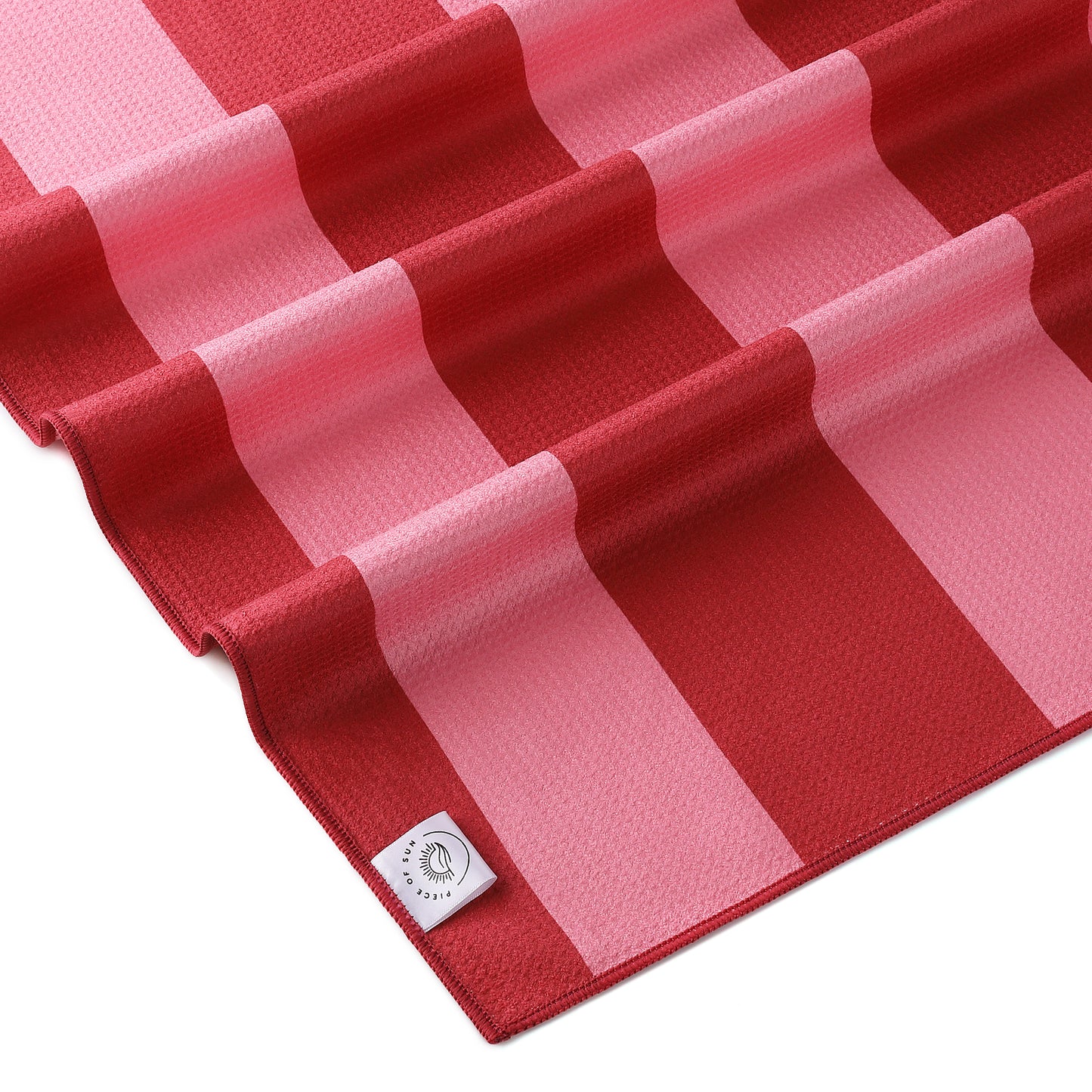 Detail van het microvezel strandlaken van Piece of Sun met roze en donkerroze strepen. Luxe wafelstructuur, ultrazacht en sneldrogend materiaal van 85% gerecycled textiel – duurzaam en comfortabel.