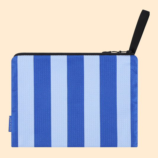 Lichtgewicht microvezel pouch in blauw-lichtblauw gestreept design van Piece of Sun®. Gemaakt van 85% gerecycled materiaal, sneldrogend en ideaal als compact opbergtasje voor strand of vakantie.
