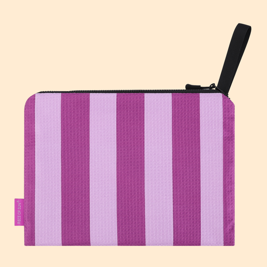 Modieuze pouch van Piece of Sun® met paars-lila strepen. Gemaakt van duurzame microvezel met wafelstructuur (85% gerecycled). Compact, lichtgewicht en ideaal als make-up tasje of reisaccessoire.